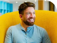 Man in blue shirt sitting in yellow chair and smiling