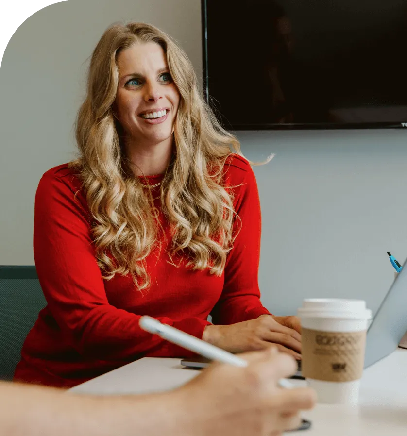 woman in red shirt happily working on a laptop